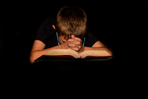 child praying over a Bible 