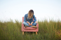 a woman slouched over in a chair in a field 