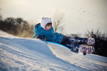 child riding on a sled in the snow