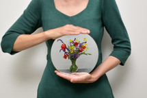 Woman Holding A Mirror And Reflection of Different Flowers In Vase