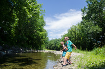 boys skipping rocks  along a creek on a warm summer day