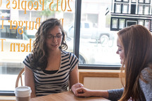 young women at a coffee shop for a Bible study praying 
