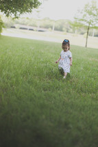 Girl walking through a grassy field.