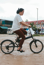 A woman riding a bicycle on a dirt road 