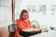 a woman sitting at a table reading a Bible 