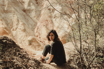 a woman sitting on a rock along a mountainside 