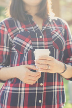 a woman in a plaid shirt holding a cup of coffee 