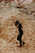 a woman hiking through sand along a mountainside 