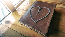 cross necklace in the shape of a heart on a Bible 