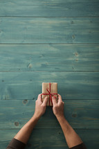 a man's hands holding a wrapped Christmas present 