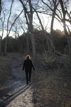 a woman walking on a path in the woods 