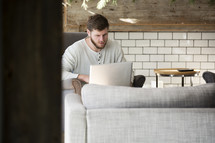 man sitting on a couch working on a laptop