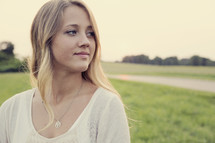 Teenage girl standing outdoors and looking back over her shoulder. 