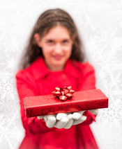 woman in a red coat holding a wrapped Christmas gift 