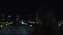 a woman standing on a city rooftop at night 