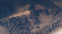 aerial view above jagged mountains below 