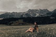 a woman sitting on a mountainside 