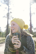 woman outdoors in a sweater holding a warm coffee mug 