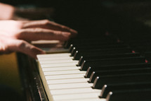 hands playing a piano 