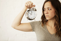 grumpy woman holding an alarm clock 