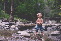 toddler boy playing in a stream 