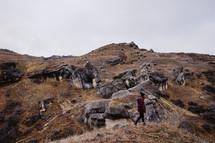 a woman walking over a rocky terrain 