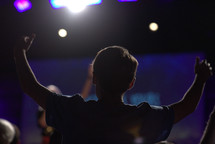 a teen boy standing with raised arms 