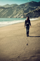 Woman walking on an empty beach in winter time