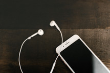 iPhone and earbuds on a wood background 