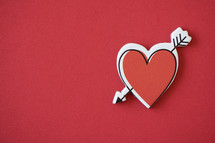 arrow through a heart sticker on red 