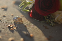 roses and wedding rings on a sidewalk 