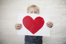 toddler boy holding a painting of a heart 