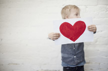 toddler boy holding a painting of a heart 