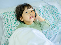 toddler girl talking on a cellphone in bed 