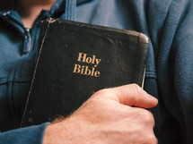 a man holding a Bible to his heart 