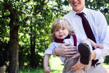 man holding a wiggly toddler boy 