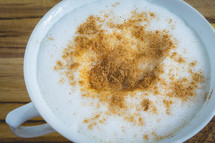 Delicious home made Cappuccino, in a white cup, on a wooden table. Home made Coffee.