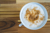 Delicious home made Cappuccino, in a white cup, on a wooden table. Home made Coffee.