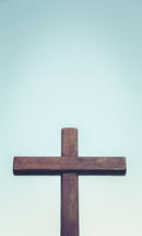 Empty wooden cross against a blue sky