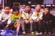 young kids sitting on a curb 