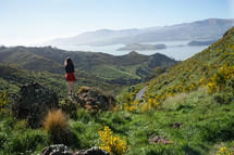 a woman standing on a mountain looking out at water views 