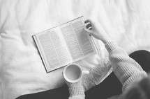 a woman sitting on a bed reading a Bible 