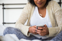 young woman sitting in bed texting 
