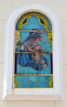 A stained glass window depicting Mary holding baby Jesus.