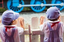 boys in conductor hats watching a train 