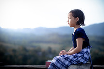 school girl praying outdoors 