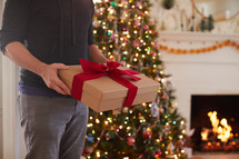 man holding a Christmas gift in a home