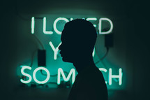 silhouette of a man standing in front of I love you so much sign 