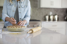 A woman in a kitchen preparing a pie.
