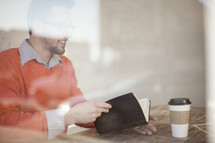 blurry image of a man reading the Bible and a coffee cup 